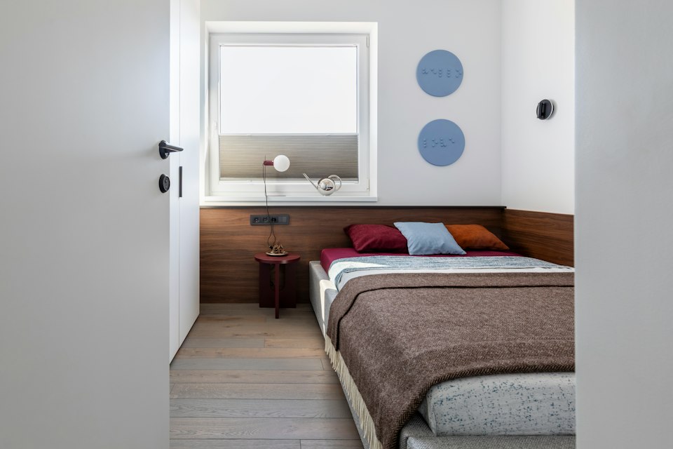 Compact bedroom with a double bed, a wood headboard panel and a window with a blind
